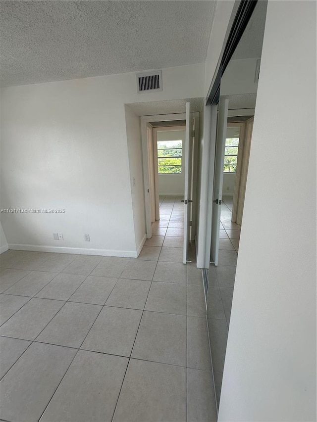 tiled spare room featuring a textured ceiling