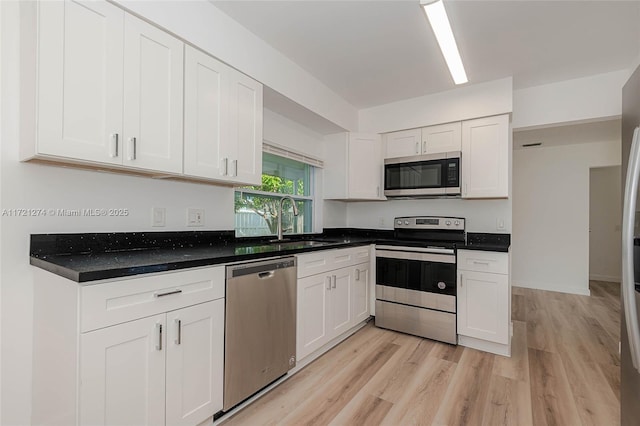 kitchen with white cabinetry, sink, light hardwood / wood-style floors, and appliances with stainless steel finishes