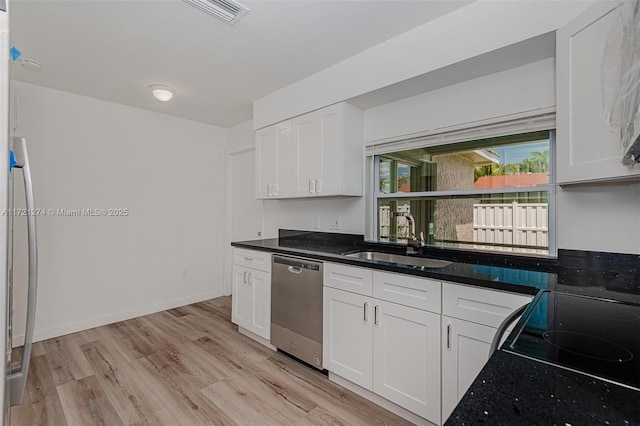 kitchen with light wood-type flooring, sink, dark stone countertops, dishwasher, and white cabinetry