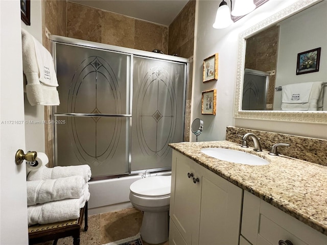 full bathroom with bath / shower combo with glass door, vanity, and toilet