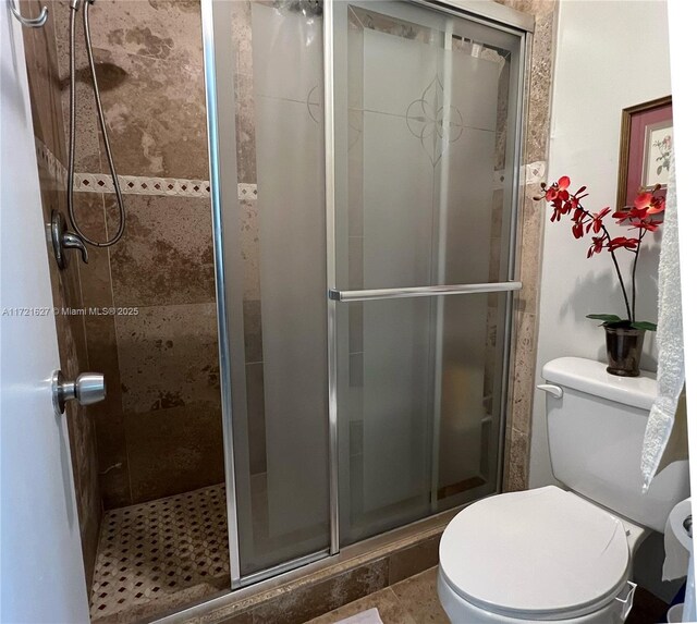 bathroom with a shower with door, tile patterned flooring, and toilet