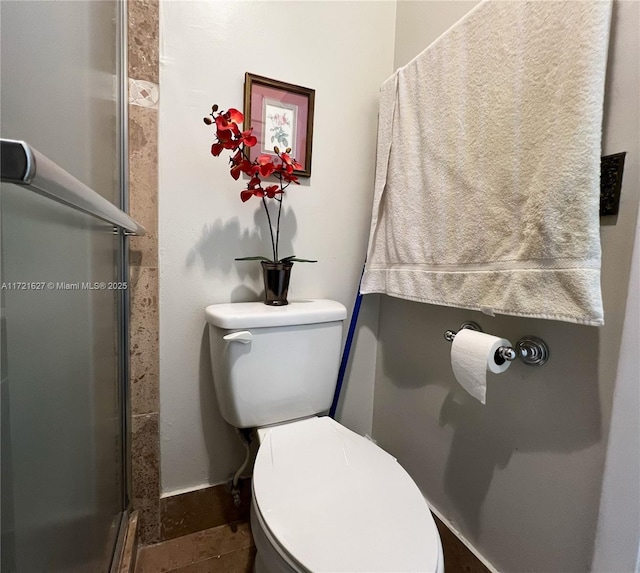 bathroom with toilet and a shower with shower door