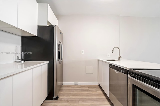 kitchen featuring light wood-type flooring, white cabinetry, sink, and appliances with stainless steel finishes