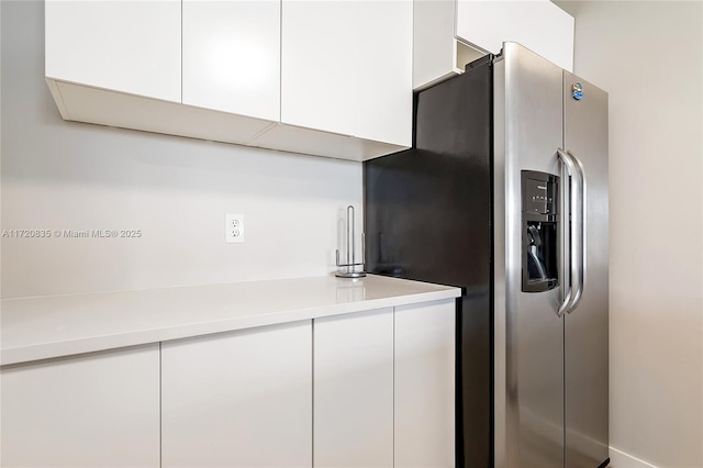 kitchen with stainless steel fridge with ice dispenser and white cabinetry