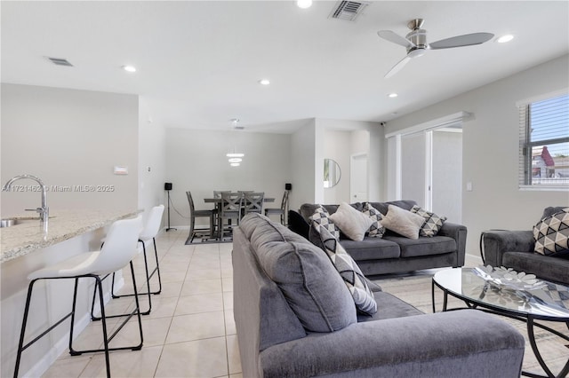 living room with ceiling fan, sink, and light tile patterned flooring