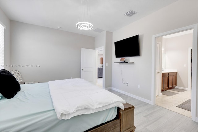 bedroom with light hardwood / wood-style floors and ensuite bath