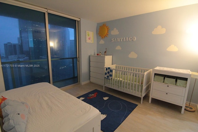 bedroom featuring a nursery area and light hardwood / wood-style floors