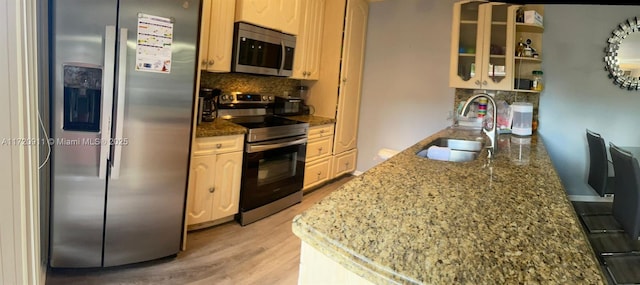 kitchen with sink, stainless steel appliances, dark stone counters, light hardwood / wood-style floors, and decorative backsplash