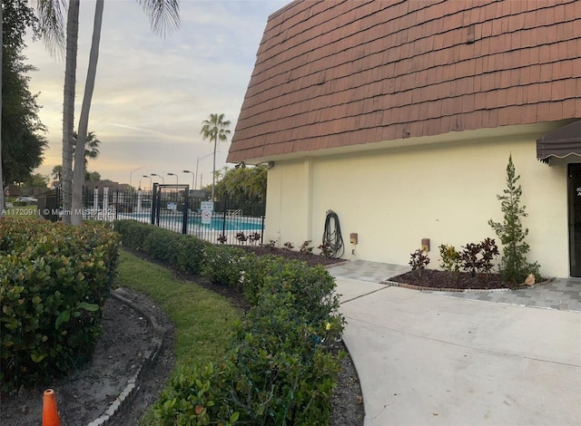 property exterior at dusk with a community pool