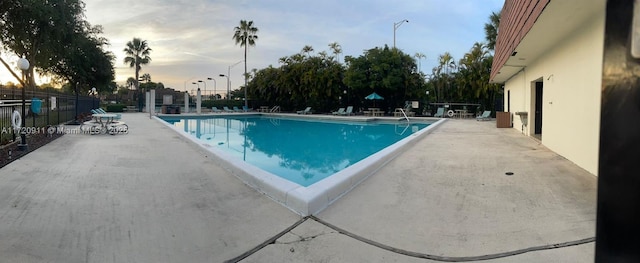 pool at dusk featuring a patio