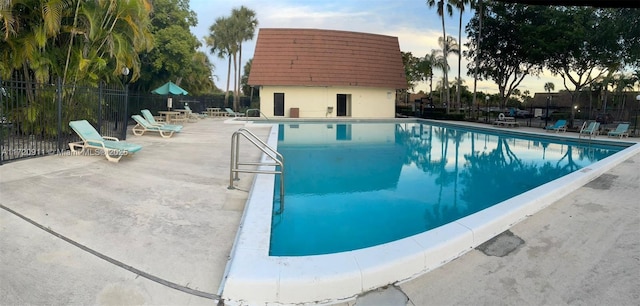 pool at dusk featuring a patio area