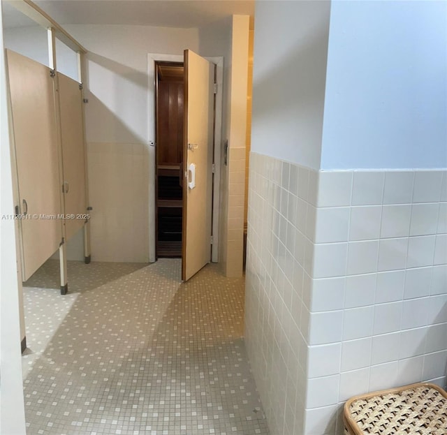 hallway with light tile patterned floors and tile walls