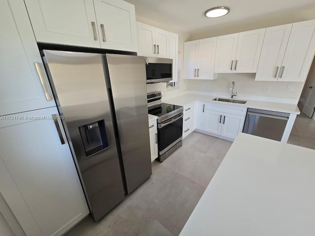 kitchen with appliances with stainless steel finishes, light tile patterned floors, white cabinetry, and sink