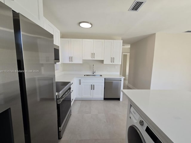 kitchen with sink, light tile patterned flooring, white cabinetry, stainless steel appliances, and washer / clothes dryer