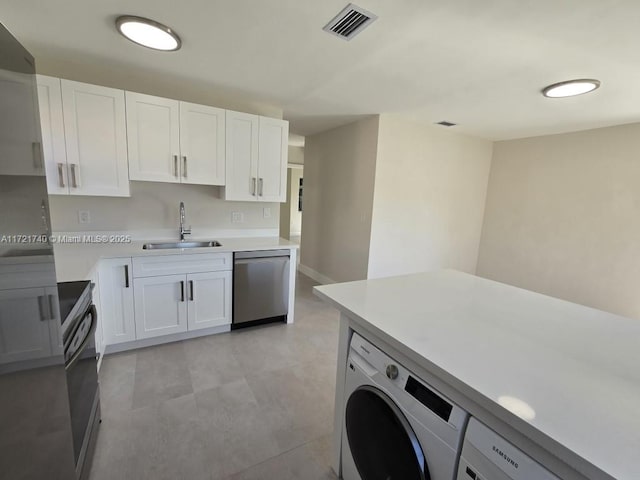 kitchen featuring white cabinetry, sink, stainless steel appliances, and washer / dryer