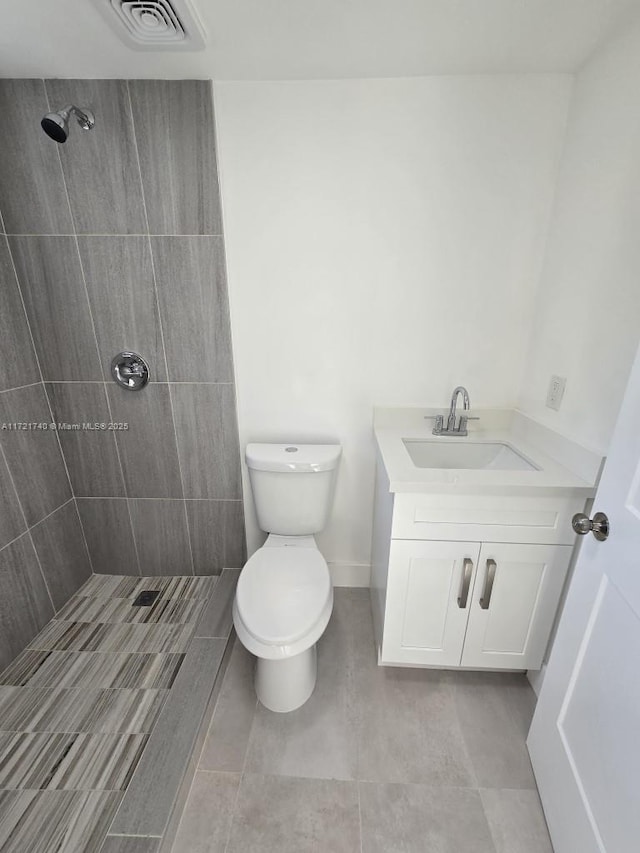 bathroom with vanity, toilet, and a tile shower