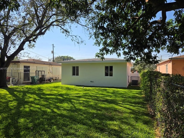 rear view of house featuring a yard and central AC