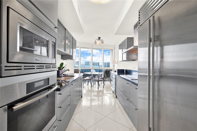 kitchen featuring sink, wall chimney exhaust hood, stainless steel appliances, gray cabinets, and light tile patterned flooring