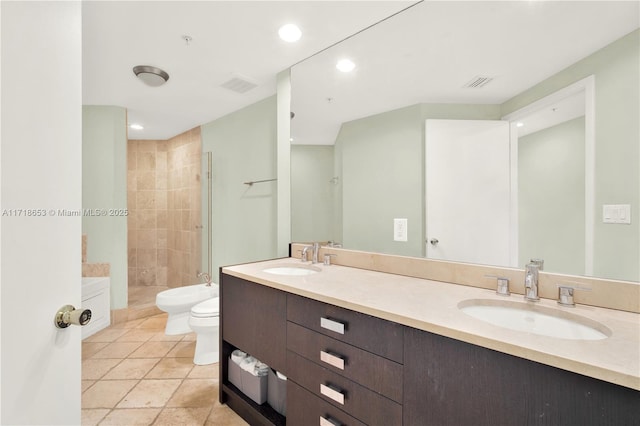 bathroom with a tile shower, vanity, toilet, and a bidet