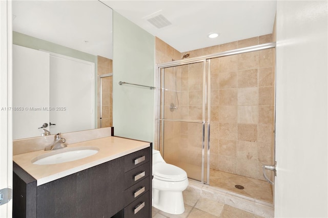 bathroom featuring vanity, toilet, and a shower with shower door