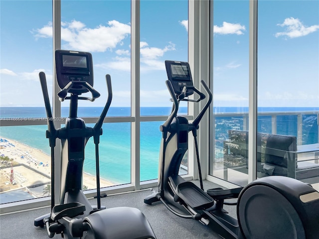 workout area featuring a view of the beach, a water view, and a healthy amount of sunlight