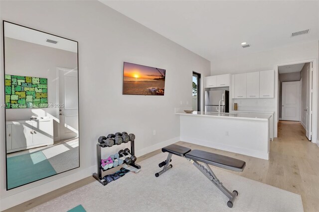 workout room featuring light hardwood / wood-style flooring and lofted ceiling