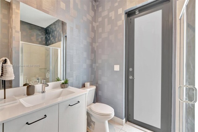 bathroom with tile patterned flooring, vanity, toilet, and an enclosed shower