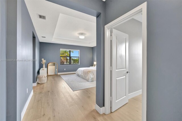 bedroom featuring light hardwood / wood-style flooring and a raised ceiling