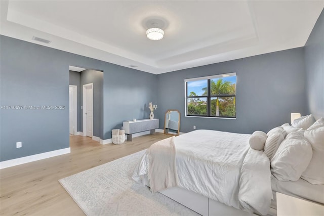 bedroom featuring a raised ceiling and light hardwood / wood-style flooring