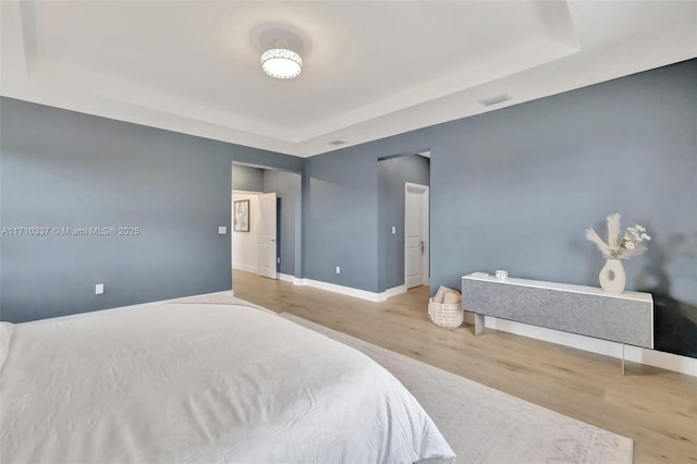 bedroom featuring hardwood / wood-style flooring and a raised ceiling