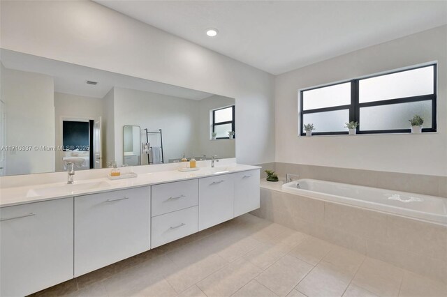 bathroom featuring vanity, tile patterned flooring, and tiled tub