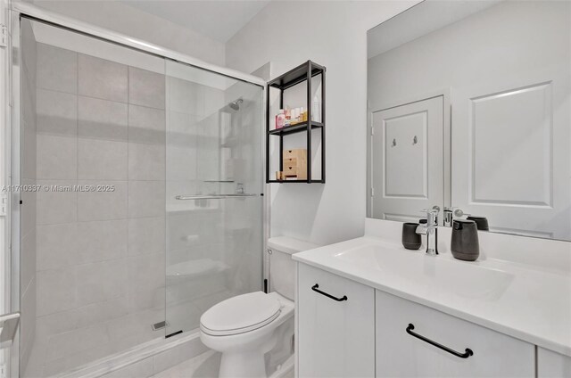 bathroom featuring vanity, toilet, and a shower with shower door