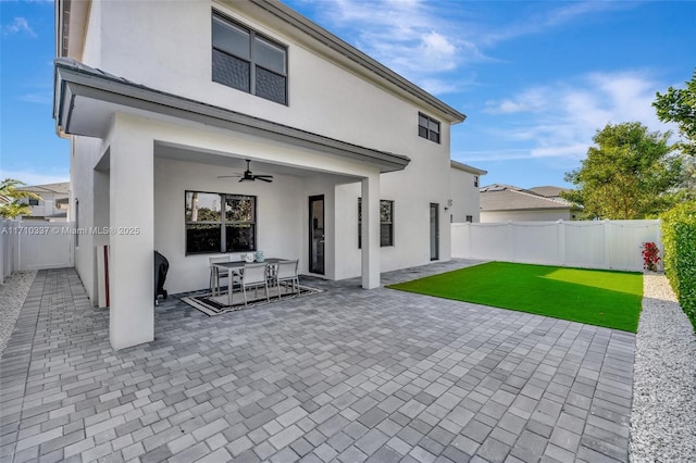 back of house featuring ceiling fan, a patio, and a lawn