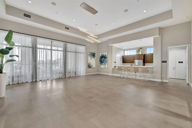 unfurnished living room featuring a towering ceiling