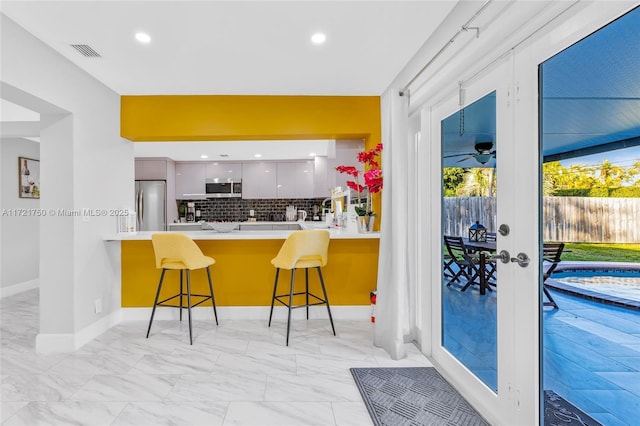 kitchen featuring white cabinets, a kitchen breakfast bar, kitchen peninsula, and stainless steel appliances