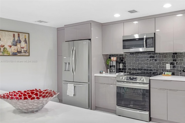 kitchen with backsplash, stainless steel appliances, and gray cabinets