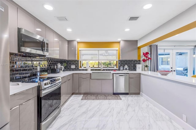 kitchen with backsplash, gray cabinets, sink, and appliances with stainless steel finishes