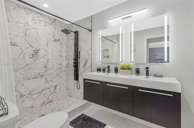 bathroom featuring a tile shower, tile patterned flooring, vanity, and toilet