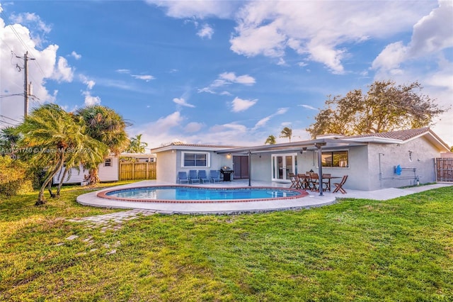 back of house with a yard, a patio, and a storage unit