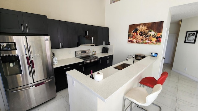 kitchen featuring sink, kitchen peninsula, a breakfast bar area, and appliances with stainless steel finishes