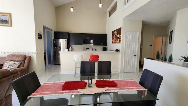 tiled dining area with a textured ceiling and a high ceiling