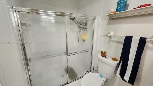 bathroom featuring toilet and a shower with shower door