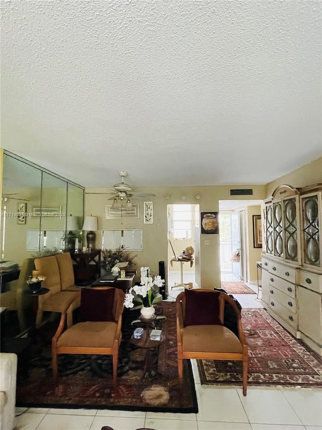 tiled living room featuring ceiling fan and a textured ceiling