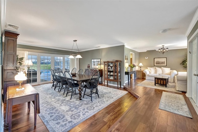 dining room featuring wood-type flooring, crown molding, and a chandelier