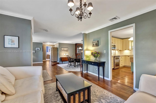 living room featuring crown molding, hardwood / wood-style flooring, and an inviting chandelier