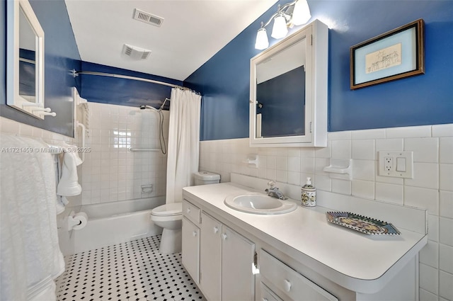 full bathroom featuring vanity, toilet, shower / bath combo with shower curtain, and tile walls