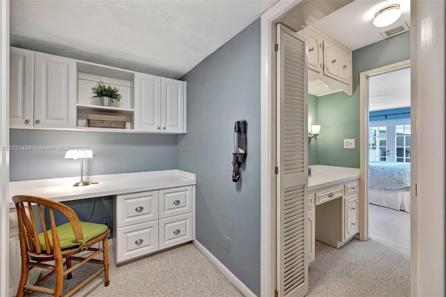 home office featuring light carpet and built in desk