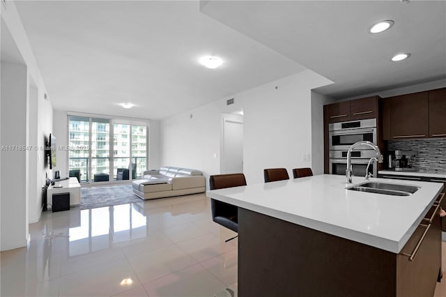 7751 NW 107th Ave Unit 509, Doral, FL 33178 - kitchen with recessed lighting, light countertops, a sink, dark brown cabinetry, and a breakfast bar area
