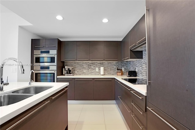 kitchen featuring a sink, dark brown cabinetry, light countertops, and stainless steel double oven