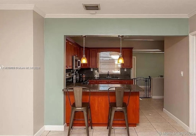 kitchen featuring light tile patterned flooring, a kitchen bar, sink, hanging light fixtures, and kitchen peninsula